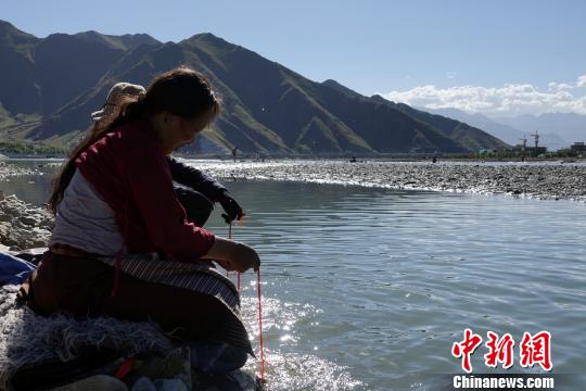 60岁的藏族老人巴金在河水中清洗法器。 孙翔 摄